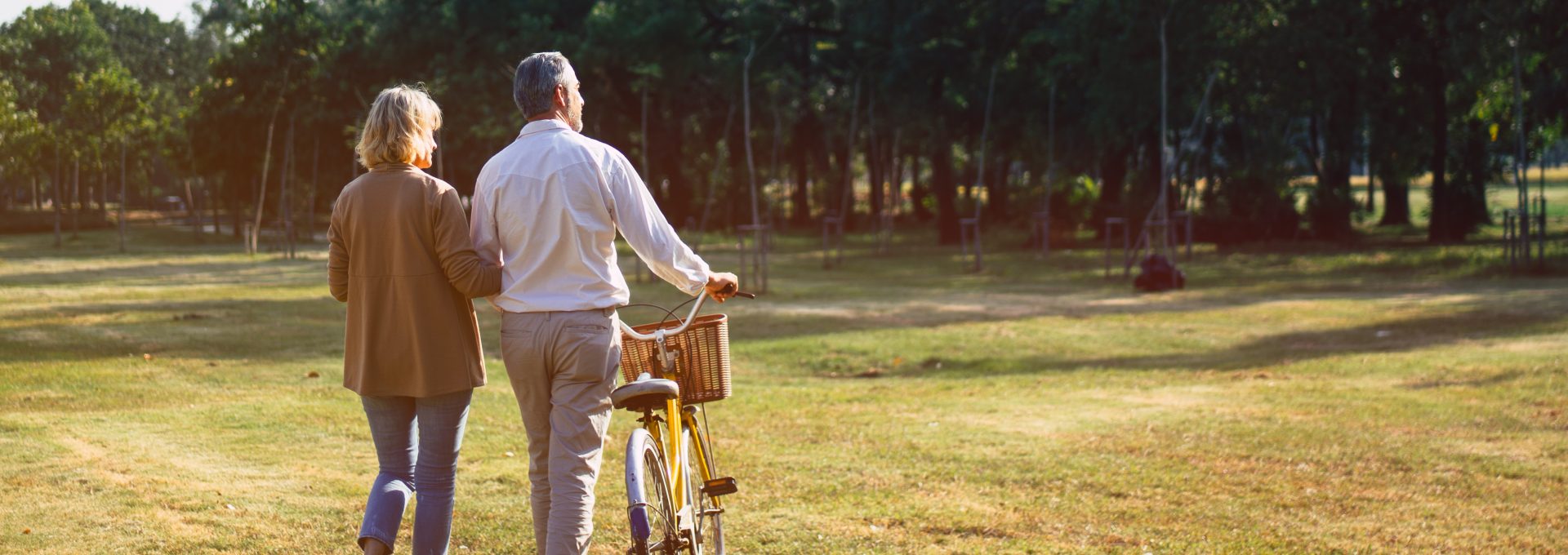 an older couple walking in a park with a bicycle at The Hudson Oaks