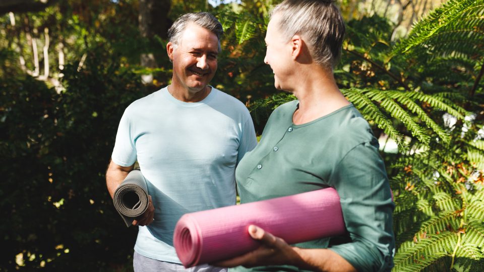 a man and woman holding yoga mats in the garden at The Hudson Oaks