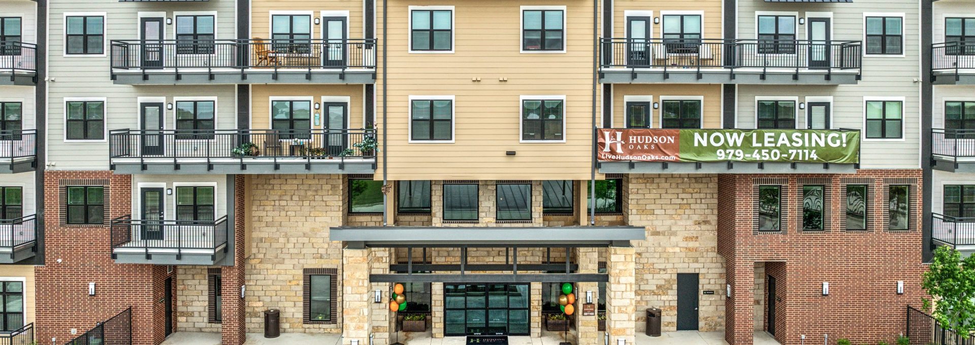 the front of an apartment building with parking lot at The Hudson Oaks