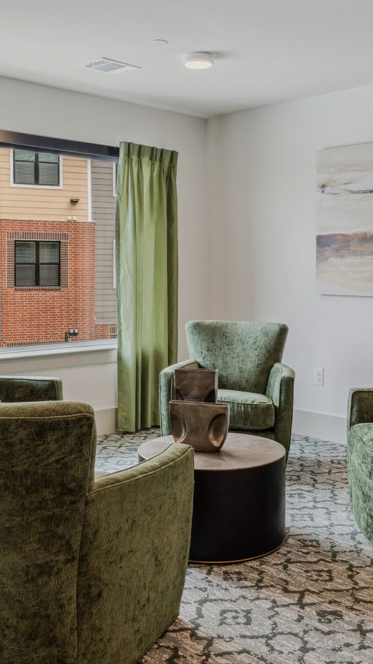 a living room with green chairs and a window at The Hudson Oaks